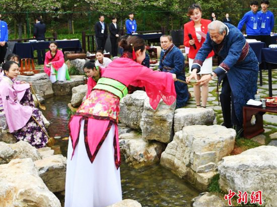 來自海內外的書法家身著晉服，在曲水邊品酒、賦詩、揮毫。
